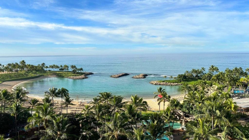 View from Aulani of its beach and cove with palm trees in the foreground