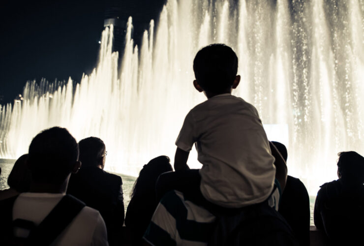 child on an adult's shoulders watching the evening fountain show at the Bellagio in Las Vegas