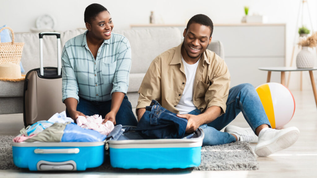 couple packing for the family with clothing in a teal suitcase
