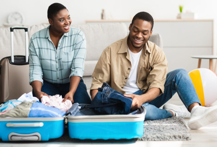 couple packing for the family with clothing in a teal suitcase