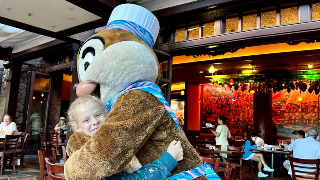 Chip or Dale hugging a child at the character breakfast at Makahiki at Aulani