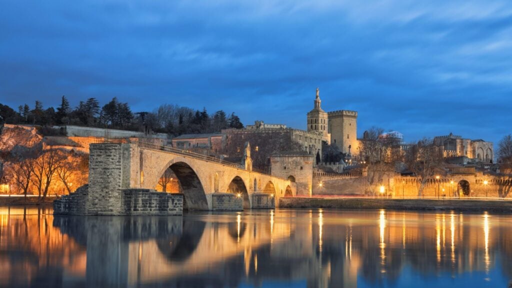 iew on Pont d'Avignon 12th century bridge and city skyline reflecting in water at dusk in Avignon, Provence, France