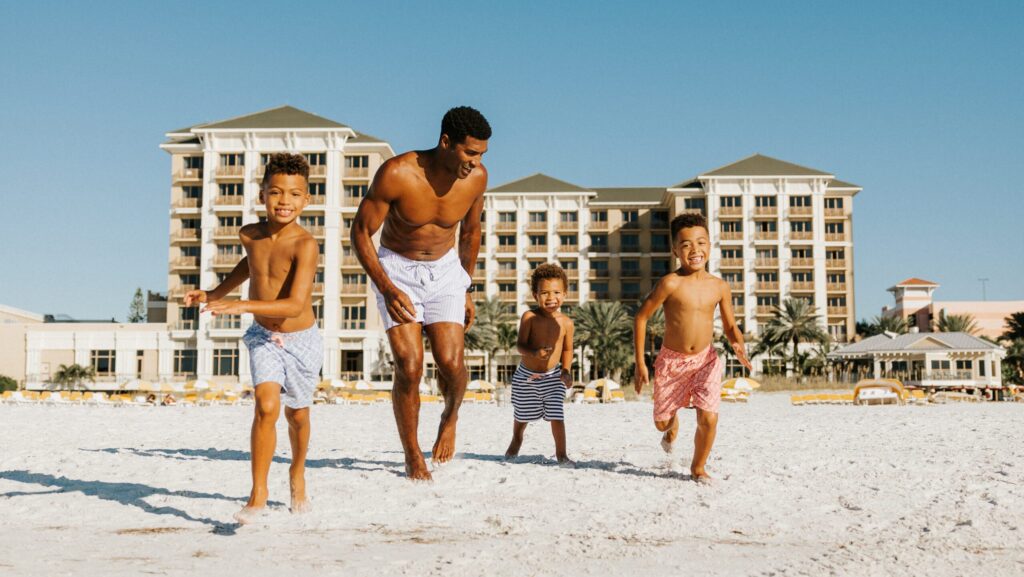 A dad and three little boys playing on the beach at Sandpearl Resort in Clearwater Beach