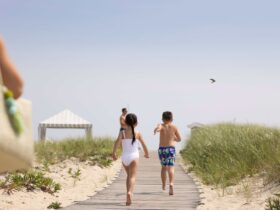 A girl and a boy running down a boardwalk to the beach