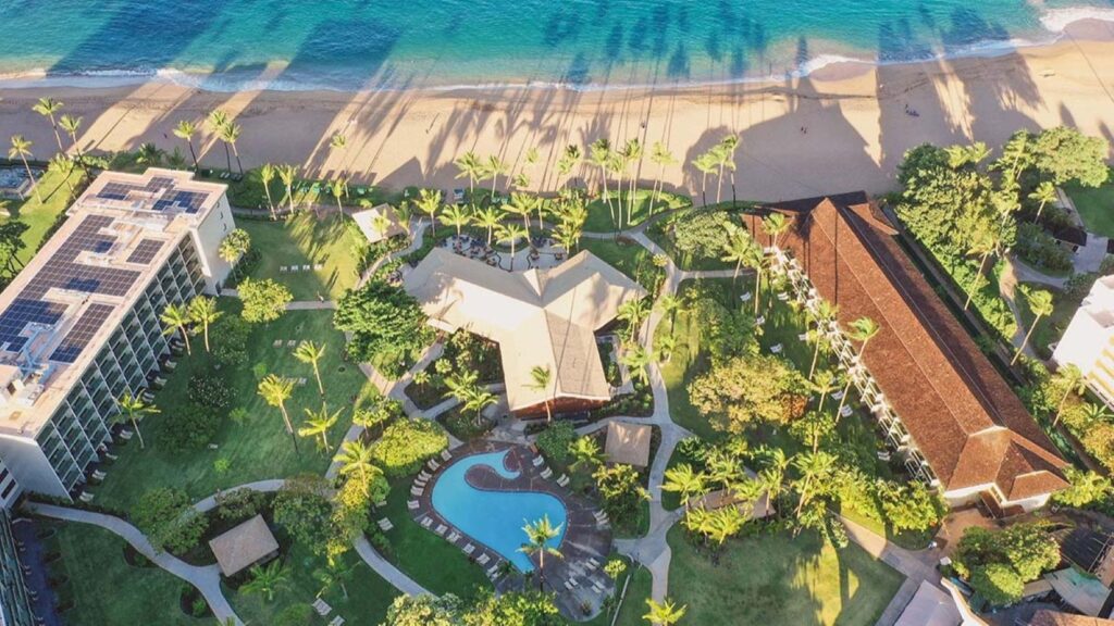 An aerial view of Outrigger Kā‘anapali Beach Resort showing it's whale-shaped pool and the beach 