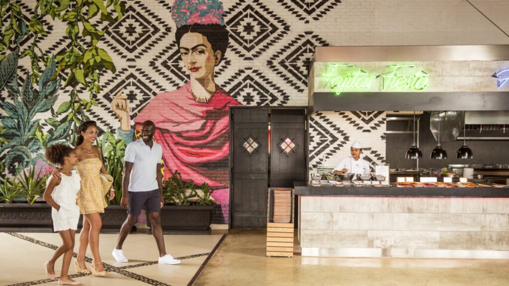 family walking into Taco Arte restaurant with view of Frida Kahlo mural in background