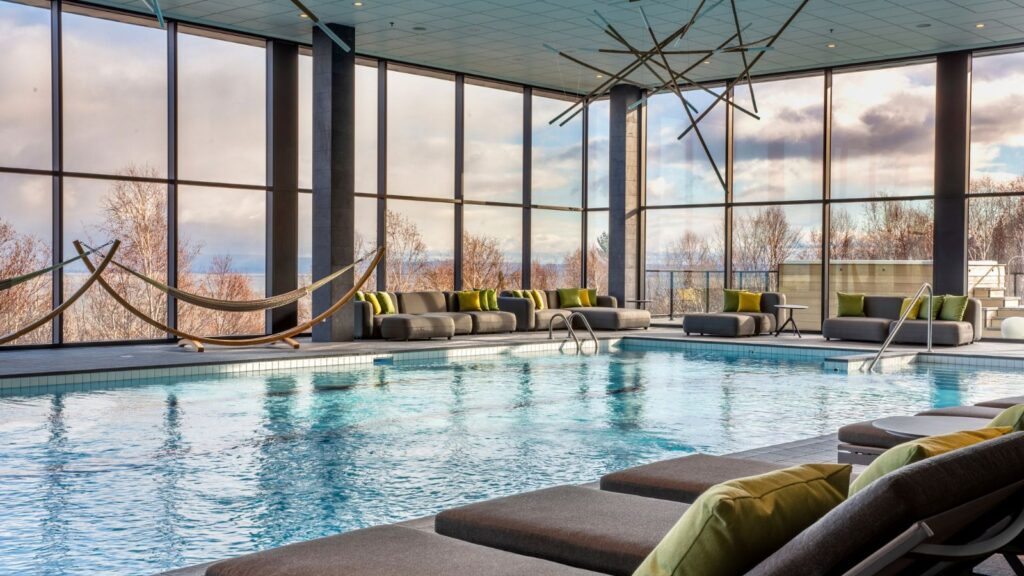 Kolam renang indoor berpemanas dikelilingi oleh jendela-jendela besar yang menghadap pemandangan (Foto: Club Med)
