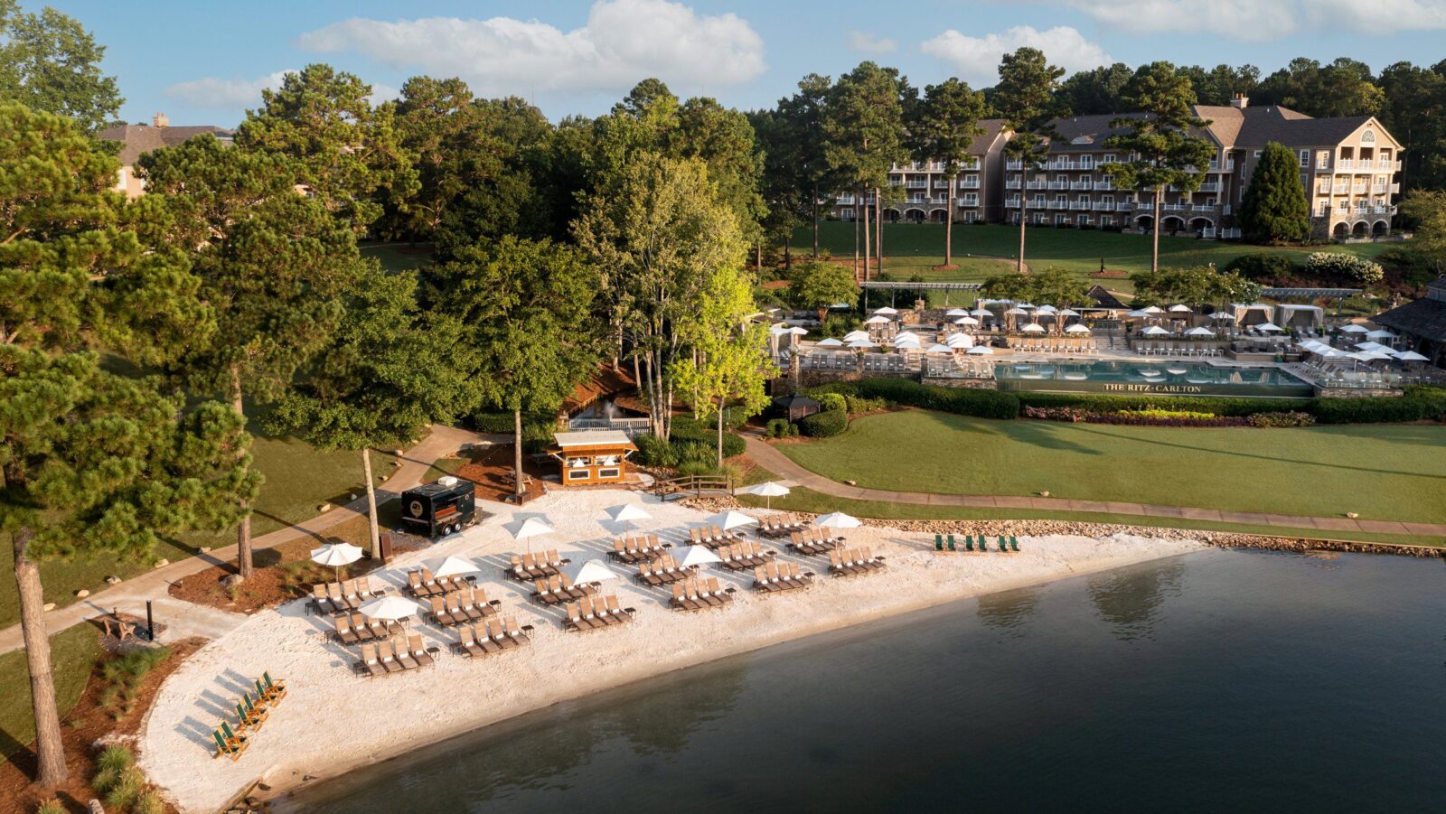 Chairs and umbrellas set up on the lake beach at The Ritz-Carlton Reynolds, Lake Oconee