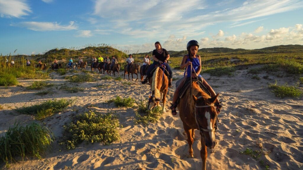 kids riding horses on the beach just before sunset on South Padre Island in Texas