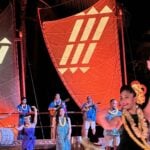 Disney Aulani luau Ka Wa'a dancers and storyteller against a nighttime background and sails