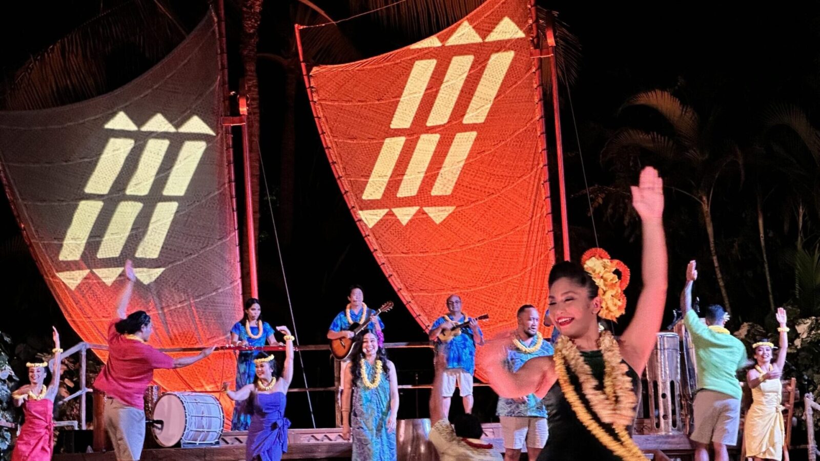 Disney Aulani luau Ka Wa'a dancers and storyteller against a nighttime background and sails