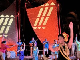 Disney Aulani luau Ka Wa'a dancers and storyteller against a nighttime background and sails