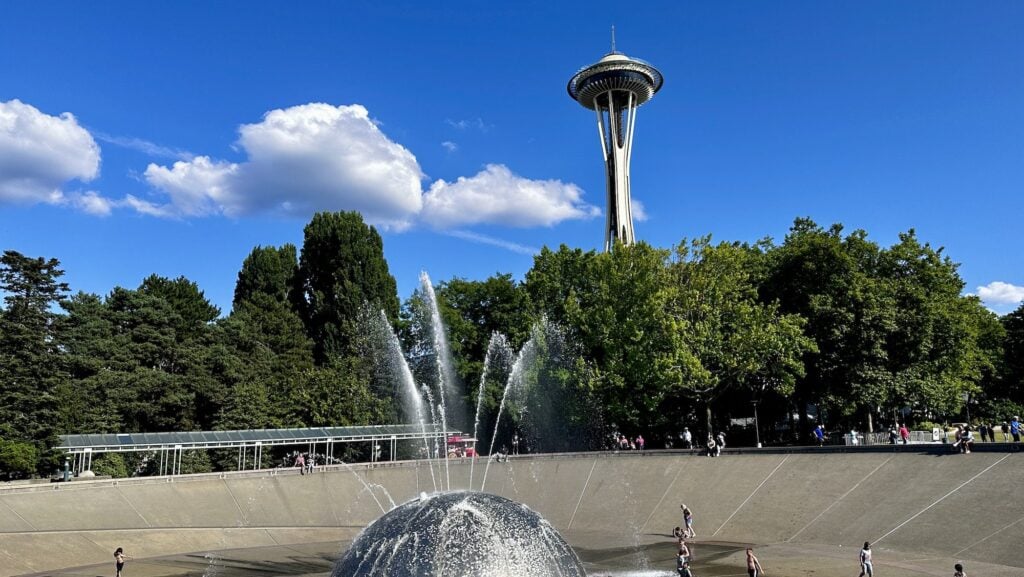view of the Seattle Space Needle and fountain with kids playing on a warm summer day