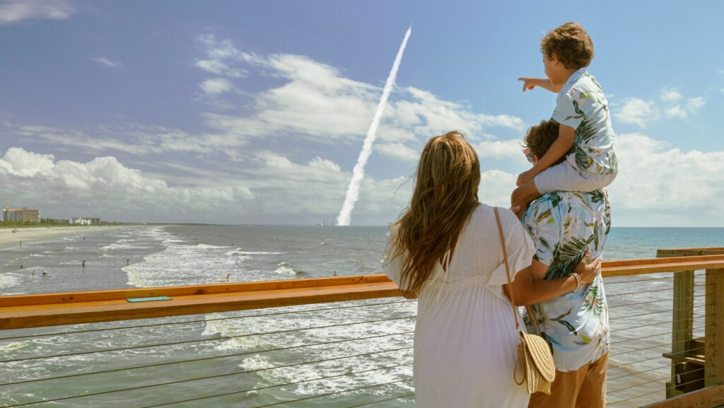 A family standing on Cocoa Beach Pier watching a rocket launch from Kennedy Space Center