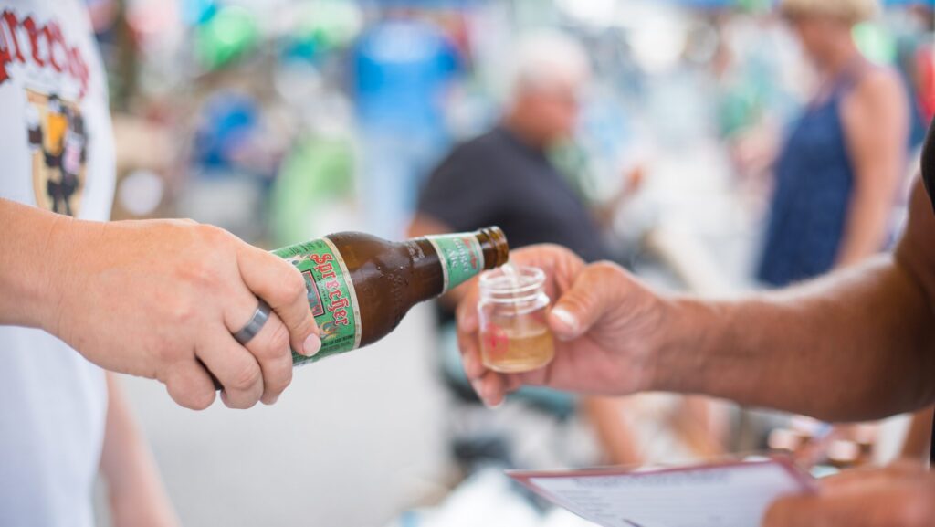 A person pouring a soda sample into a small glass at the Sebring Soda Festival