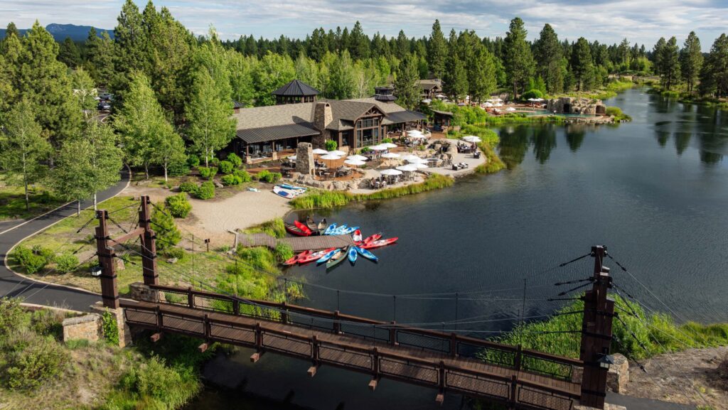 An aerial view of the Lakehouse at Sunriver Resort with kayaks, a restaurant, and a pool complex in view