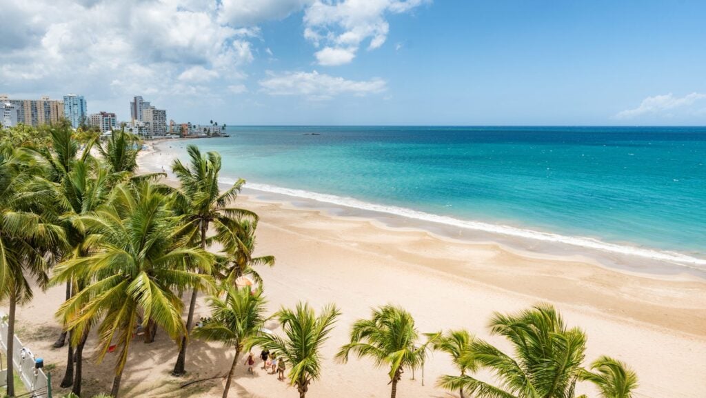 View of Isla Verde Beach in Puerto Rico with palm trees and azure water, with hotels in the background