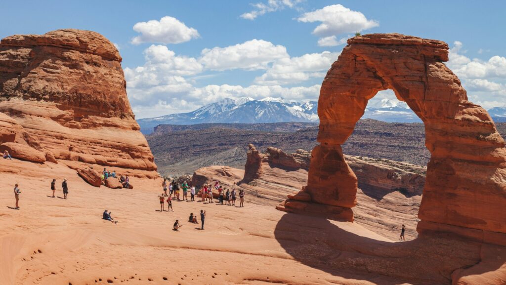 Lots of visitors admiring and taking pictures of Delicate Arch at Arches National Park