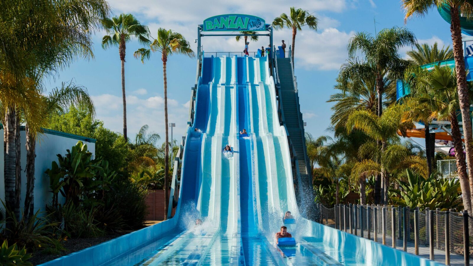 People riding on mats down blue waterslides