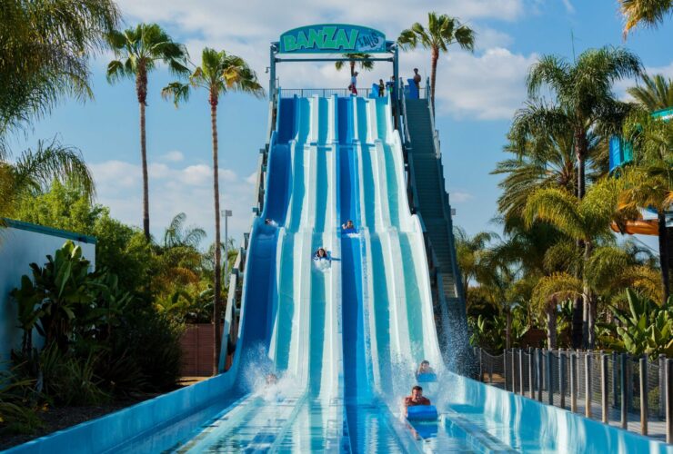 People riding on mats down blue waterslides