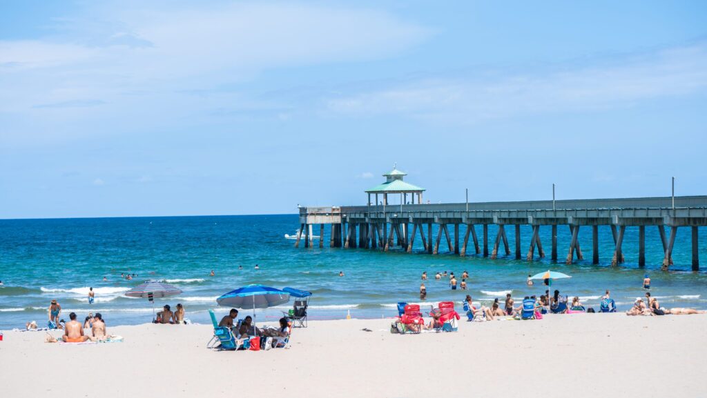 People on Deerfield Beach with the International Fishing Pier in the background