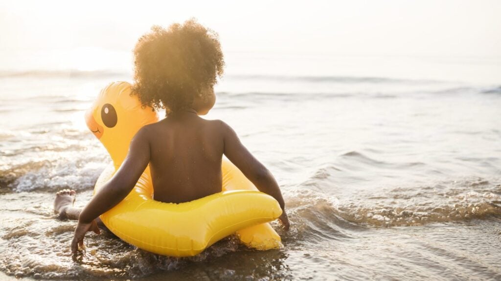 child with rubber duck floaty toy on beach in Cape Town