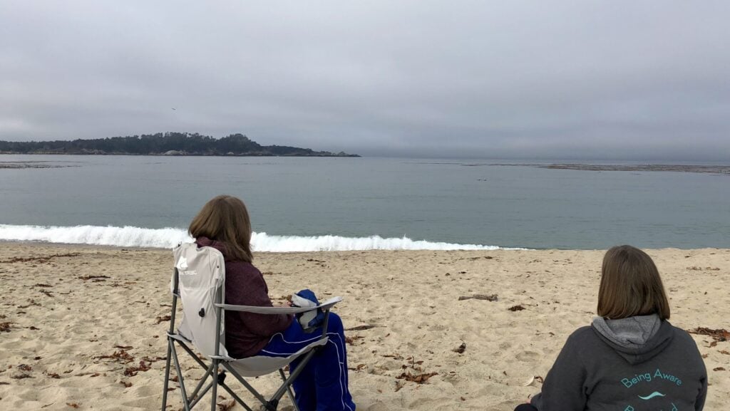 two people sitting looking out at the Pacific from the Carmel River Beach