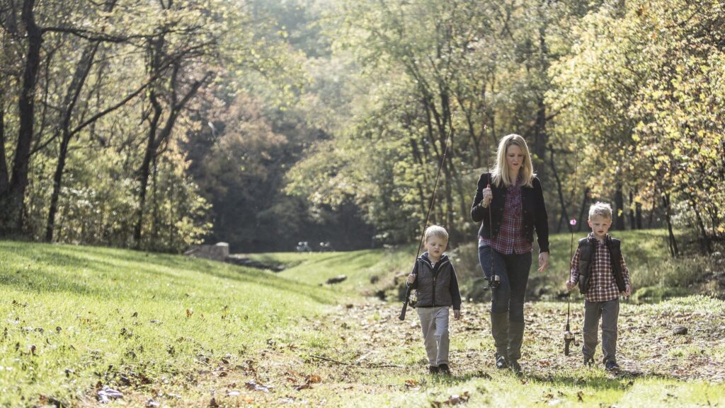 A mom and two little boys with fishing rods at Dogwood Canyon Nature Park