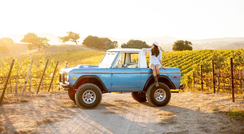 A woman sitting on a blue truck by vineyards in Buellton, CA