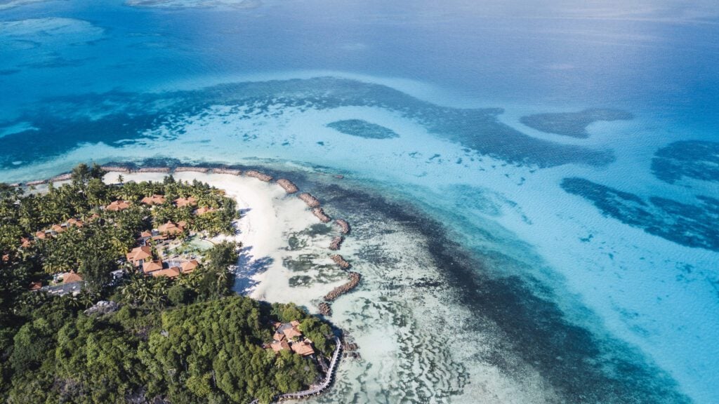 aerial view of Club Med Seychelles, with bright azure water, beach, reef, and resort visible