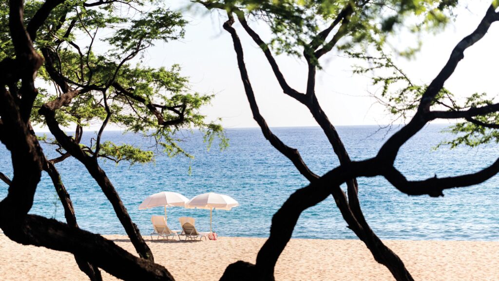 View of two beach chairs and umbrellas on the beach in Lanai