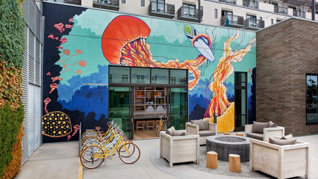 Exterior of SpringHill Suites Oceanside's Board and Bike Shop, with large mural of jellyfish and sealife plus bikes lined up