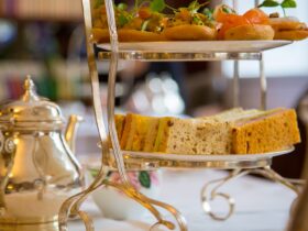 Afternoon tea setup with tiered sandwich tower and silver teapot