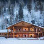 A cabin and tree decorated for the holidays in the snow