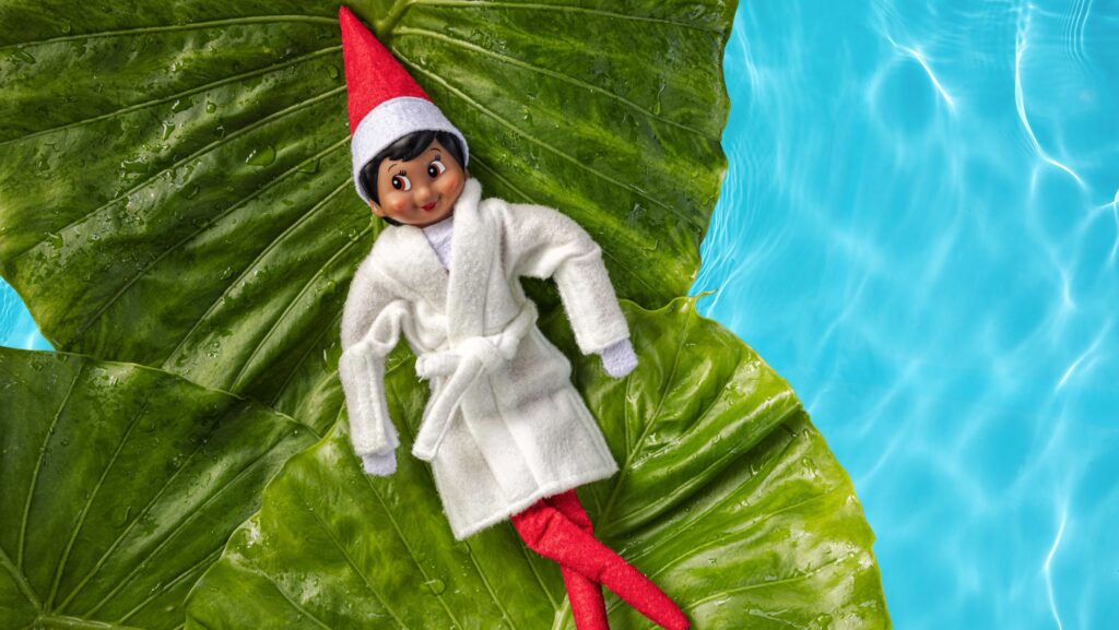 An Elf on the Shelf wearing a robe floating on a leaf in a pool at Beaches Resorts