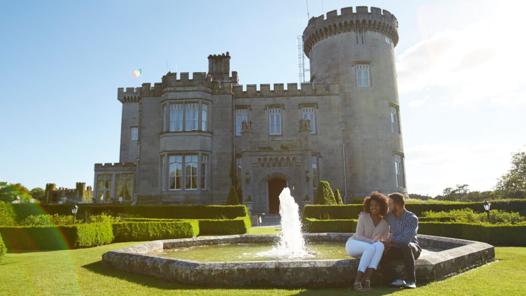 A couple sitting by a fountain in front of a castle