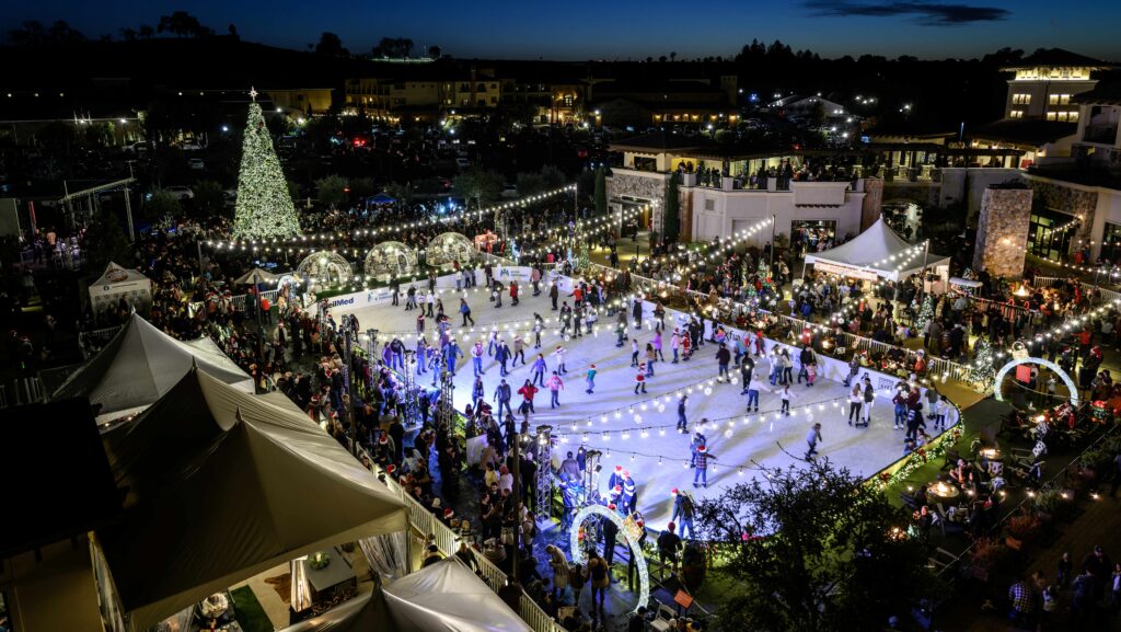 A nighttime aerial view of the ice rink at Meritage Resort all lit up with people ice skating