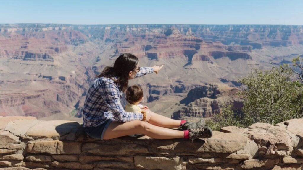 Parent and toddler perched on a wall looking out over the Grand Canyon (Photo: Envato/westend61)