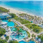 An aerial view of the beach, water park, and pools at Sandos Playacar