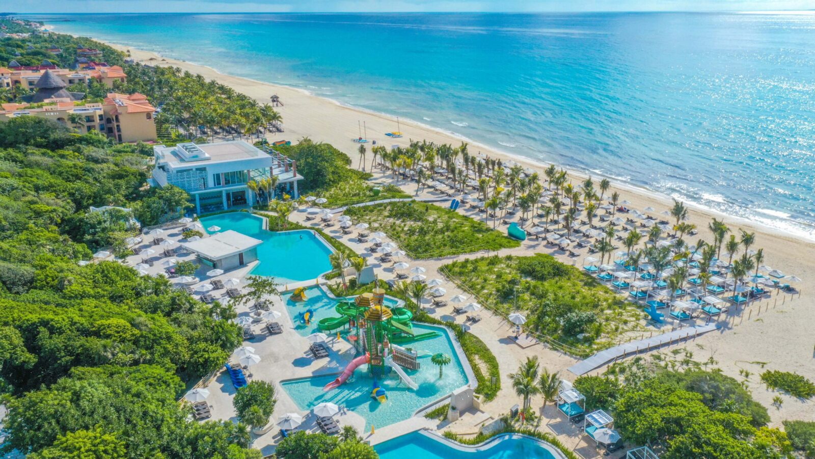 An aerial view of the beach, water park, and pools at Sandos Playacar
