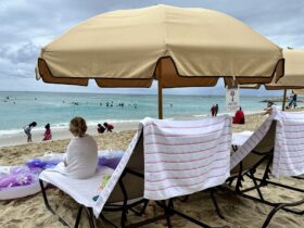 child sitting on a Waikiki beach chair rental wrapped in a towel looking out at the water
