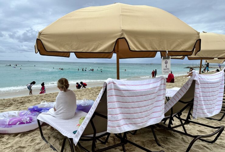 child sitting on a Waikiki beach chair rental wrapped in a towel looking out at the water