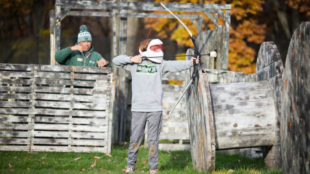 Teen using bow and arrow under supervision