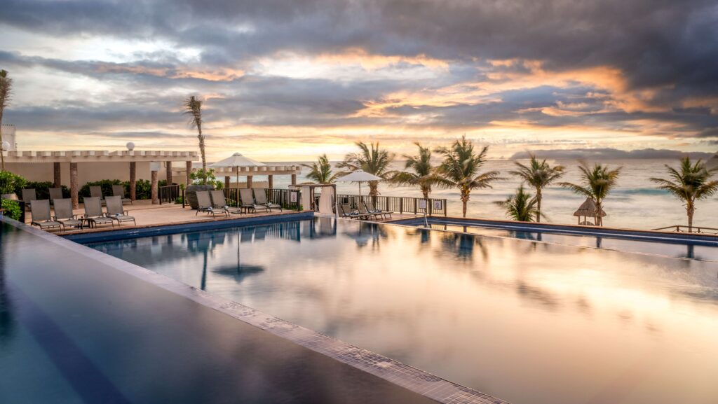 A pool overlooking the beach at sunset in Cancun