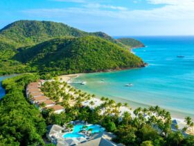 An aerial view of Carlisle Bay resort with water, the beach, boats, and green hills