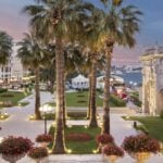 view of grounds of Ciragan Palace Kempinski Istanbul in early evening with view of Bosphorus and bridge in background