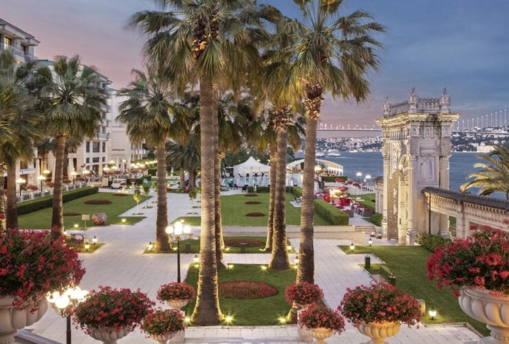 view of grounds of Ciragan Palace Kempinski Istanbul in early evening with view of Bosphorus and bridge in background