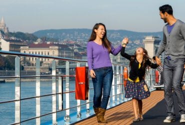 Parents and child on an Adventures by Disney Danube River Cruise, laughing on deck