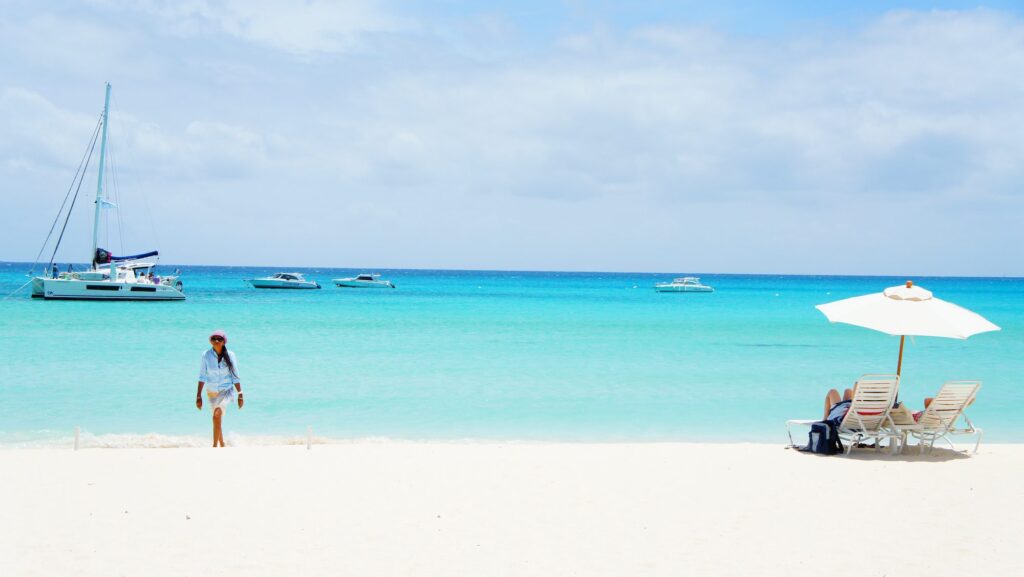 beach in anguilla with person walking and boat in background