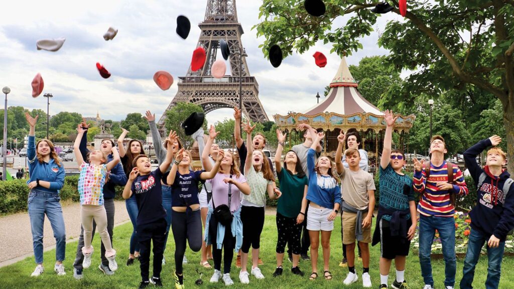 Tauck Bridges group of kids in front of the Eiffel Tower in Paris throwing berets